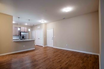 An empty living room and kitchen with wood flooring